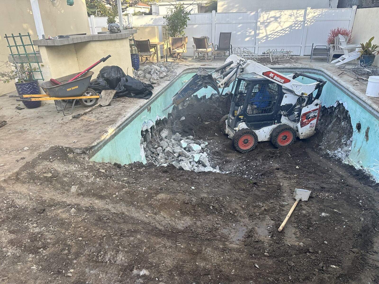 Excavator demolishing a residential swimming pool in Southern California